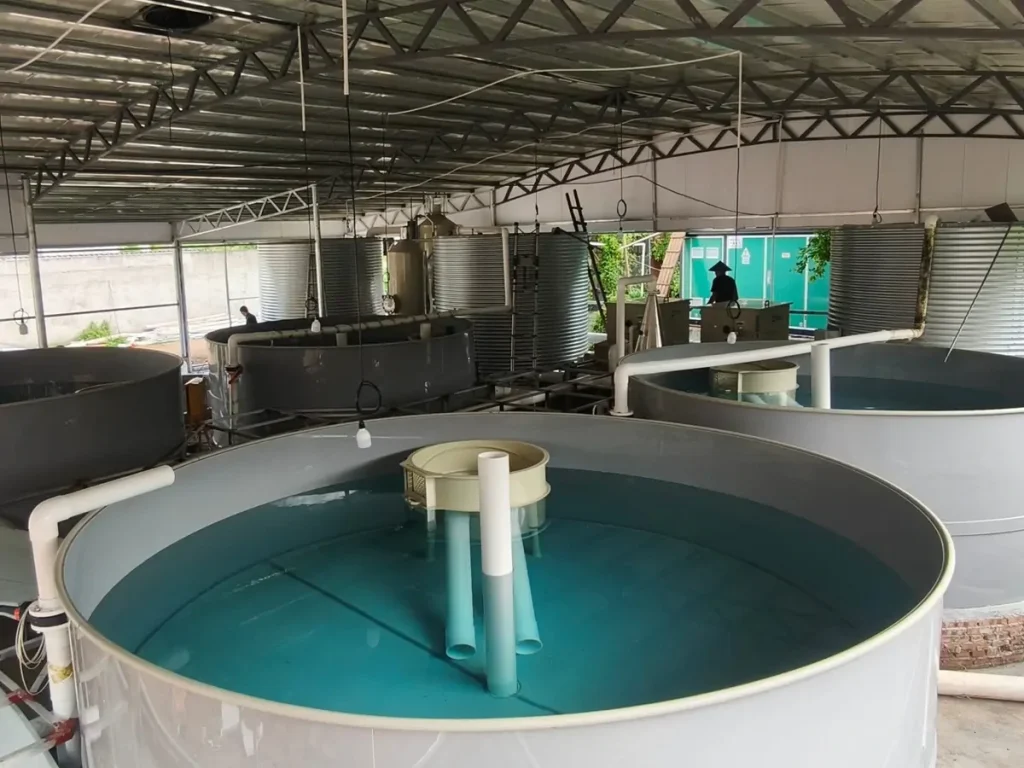 Water-filled circular tank with central pipes and treatment vessels behind it.