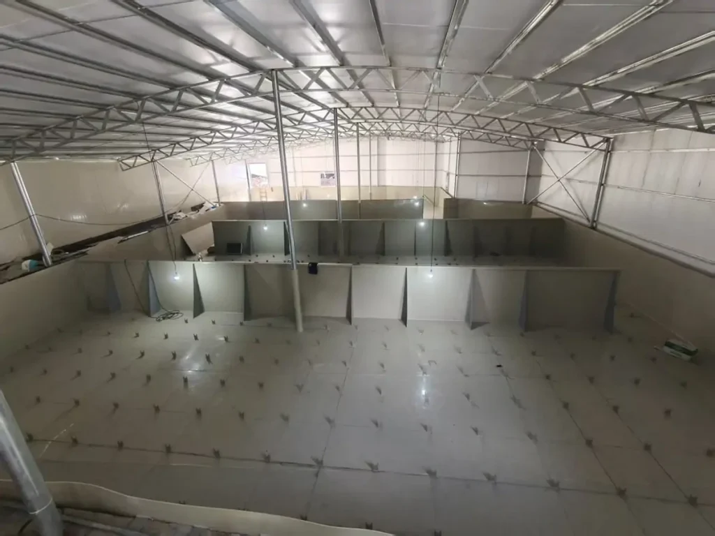 Empty rectangular indoor basin with small pipe outlets across its floor.