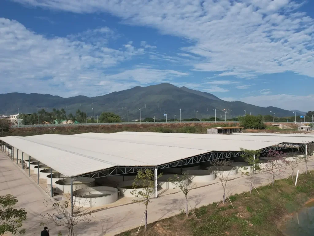 Large canopy above the culture tanks with mountains in the background.